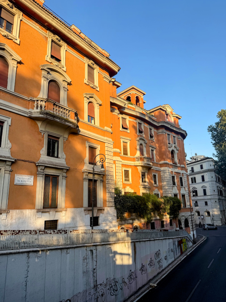 An orange building with white moulding around the doors and windows in Italian architecture.