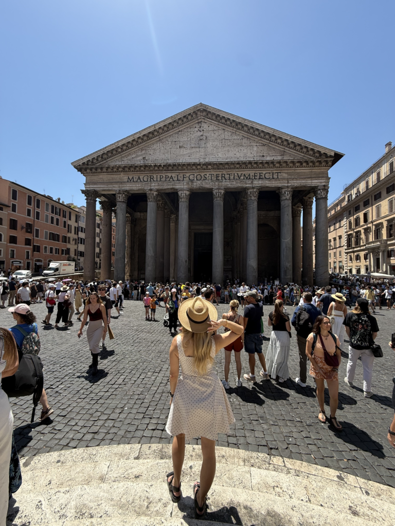 A view of the front entrance of the Pantheon in Rome, with a woman before the building facing the Pantheon.