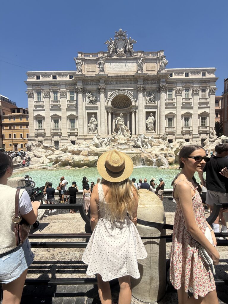 Front view of the Trevi Fountain in Rome, a large white marble fountain that looks like a building.