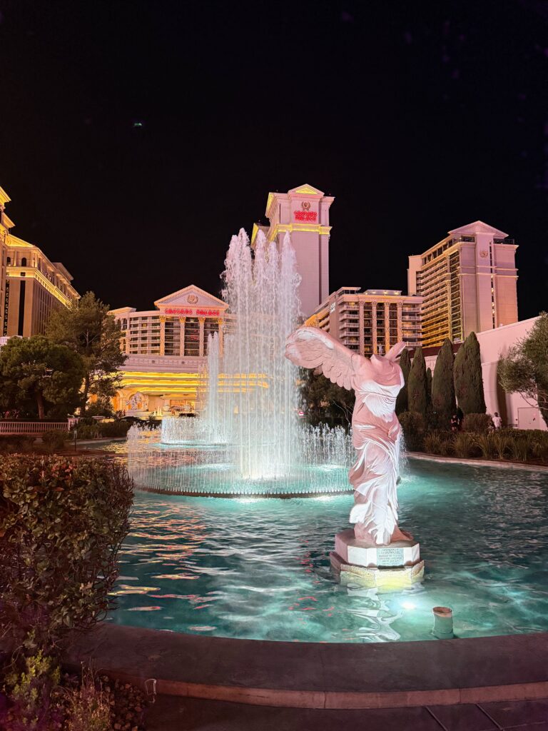 Exterior front of Caesars Palace in Las Vegas with fountain and winged statue in front.